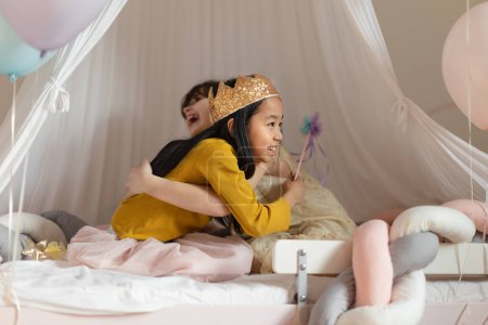 Téléchargez les photos : Filles heureuses jouant sur princesse dans la chambre. - en image libre de droit