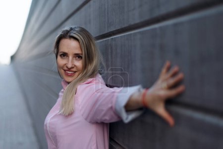Téléchargez les photos : Jeune femme blonde debout devant un mur de béton. - en image libre de droit