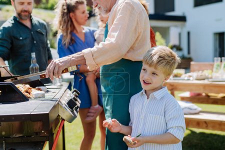 Téléchargez les photos : A multi generation family grilling outside on backyard in summer during garden party - en image libre de droit