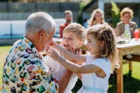 Téléchargez les photos : Petits enfants s'amuser avec leur grand-père à la fête barbecue en plein air. - en image libre de droit