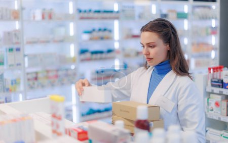 Photo for Young pharmacist checking medicine stock in a pharmacy. - Royalty Free Image
