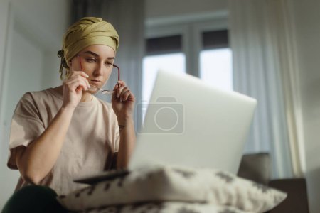 Foto de Mujer joven con cáncer trabajando en el portátil en el apartamento. - Imagen libre de derechos
