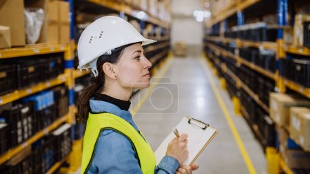 Téléchargez les photos : Warehouse female worker checking up stuff in warehouse. - en image libre de droit
