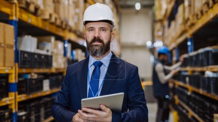 Photo for Manager in suit controlling goods in warehouse. - Royalty Free Image