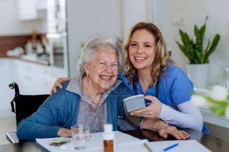 Nurse giving pills to senior woman in her home.