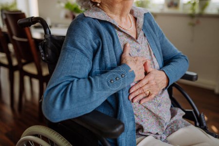 Foto de Primer plano de la mujer mayor en silla de ruedas con dolor en el pecho. - Imagen libre de derechos