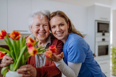 Photo for Senior woman and nurse with a tulip bouquet. - Royalty Free Image