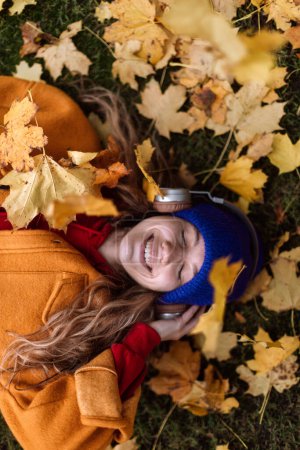 Photo for Young woman listening music outdoor,lying in the autumn nature. - Royalty Free Image