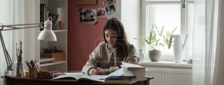 Foto de Joven adolescente estudiando y haciendo deberes en su habitación. - Imagen libre de derechos