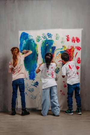 Téléchargez les photos : Vue arrière d'enfants heureux avec des couleurs de doigts et des t-shirts peints. - en image libre de droit