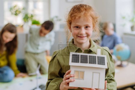 Foto de Niña posando con un modelo de casa con sistema solar durante la lección escolar. - Imagen libre de derechos