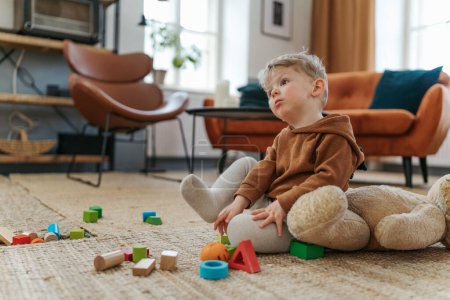 Téléchargez les photos : Petit garçon assis sur le tapis et jouant avec les cubes. - en image libre de droit