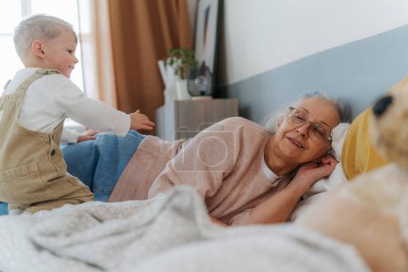 Photo for Grandmother lying with her grandson in a bed. - Royalty Free Image