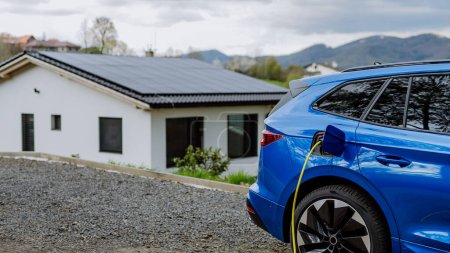 Téléchargez les photos : Gros plan sur la recharge d'une voiture électrique près d'une maison familiale. - en image libre de droit