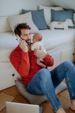 Téléchargez les photos : Père tenant son nouveau-né pleurant bébé pendant qu'il travaillait sur un ordinateur portable. - en image libre de droit