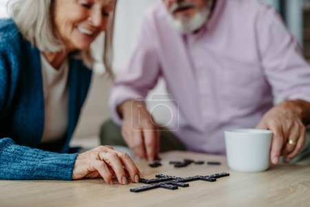 Photo for Senior couple playing dominoes game at home. - Royalty Free Image