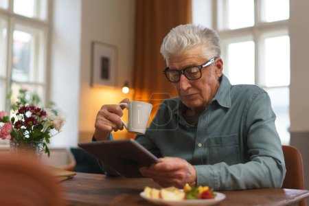 Téléchargez les photos : Homme âgé lisant quelque chose dans une tablette numérique. - en image libre de droit