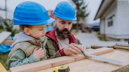 Photo for Father and his little son working together in front of their unfinished house. - Royalty Free Image