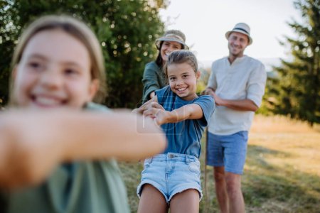 Téléchargez les photos : A young family with happy kids having fun together outdoors pulling rope in summer nature. - en image libre de droit