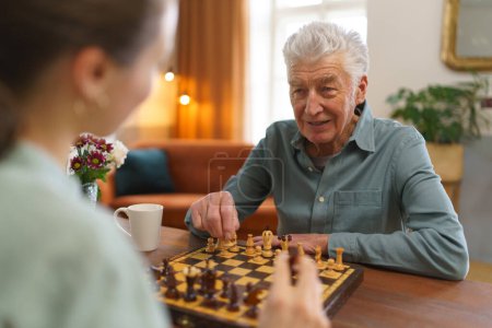 Photo for Senior man playing chess with his caregiver. - Royalty Free Image