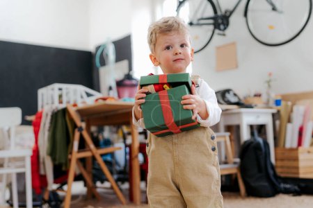 Foto de Sorprendido niño recibiendo un regalo. Feliz niño sosteniendo y abriendo caja de regalo. - Imagen libre de derechos