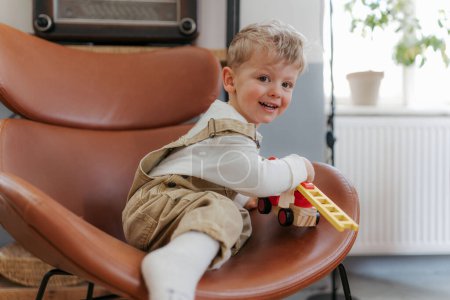 Foto de Feliz niño jugando con el juguete rojo camión de bomberos en la sala de estar. - Imagen libre de derechos