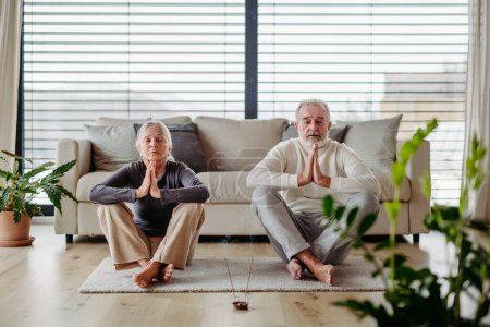 Foto de Pareja mayor está haciendo yoga juntos en la sala de estar. concepto de estilo de vida saludable. - Imagen libre de derechos