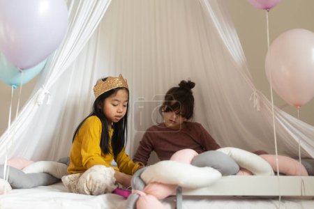 Téléchargez les photos : Filles heureuses jouant princesse dans la tente de jeu intérieure. - en image libre de droit