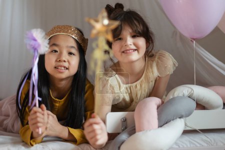 Foto de Chicas felices jugando princesa con varitas de princesa en la tienda de juegos de interior. - Imagen libre de derechos