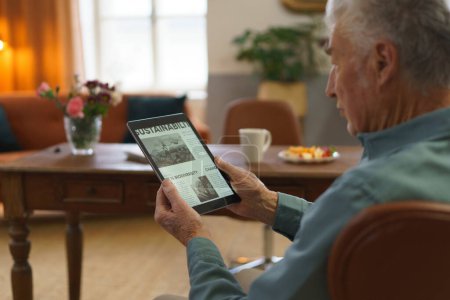 Téléchargez les photos : Homme âgé lisant des nouvelles dans une tablette numérique. - en image libre de droit