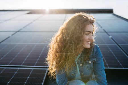 Photo for Portrait of young woman, owner on roof with solar panels. - Royalty Free Image