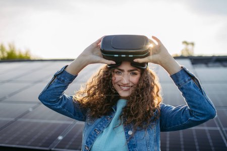 Foto de Mujer joven con gafas virtuales en un techo con paneles solares. - Imagen libre de derechos