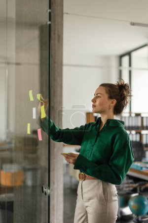 Téléchargez les photos : Une jeune femme prend des notes au bureau. Brainstorming, techniques de mind mapping. - en image libre de droit