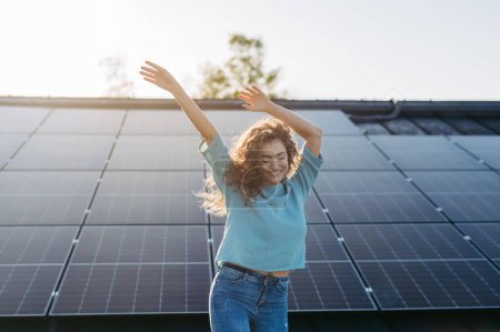 Foto de Retrato de mujer joven excitada, propietario en el techo con paneles solares. - Imagen libre de derechos