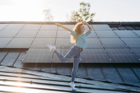Foto de Retrato de mujer joven excitada, propietario en el techo con paneles solares. - Imagen libre de derechos