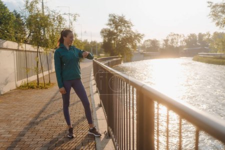 Photo for Young woman runner checking her performance on smartwach after workout session. Athletic girl preparing for a morning jogging. Outdoor Workout concept. - Royalty Free Image