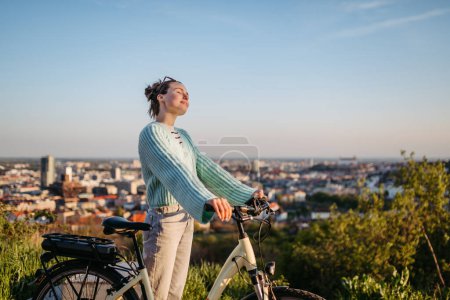 Photo for Young woman on an electro bicycle, concept of commuting and ecologic traveling. - Royalty Free Image