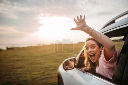 Photo for Happy woman driving her new electric car in a city. - Royalty Free Image