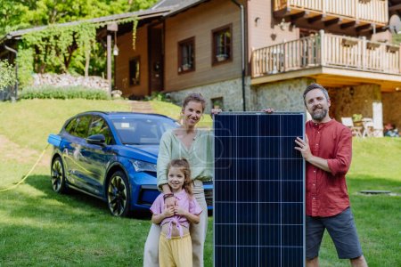 Photo for Happy family posing with a photovoltaics panel during their electric car charging. - Royalty Free Image