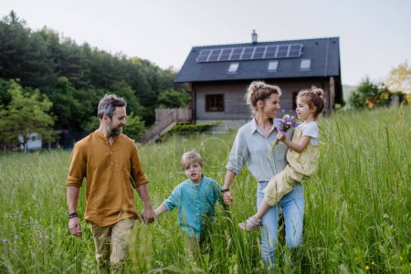 Photo for Happy family in front of their house with a solar panels on the roof. - Royalty Free Image