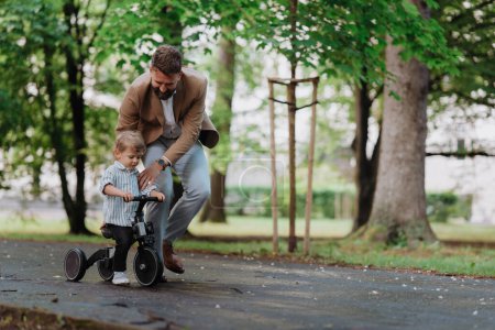Alleinerziehender Vater mit seinem kleinen Sohn, der zusammen Zeit in einem öffentlichen Park verbringt. Berufstätige Eltern verbringen nach Feierabend Zeit mit ihrem Sohn.