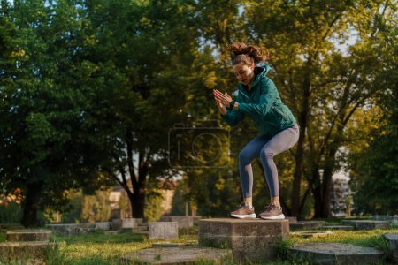 Photo for Full lenght portrait of beautiful fitness woman doing squat box jumps in the park. Workout at the park. Outdoor workout concept. - Royalty Free Image