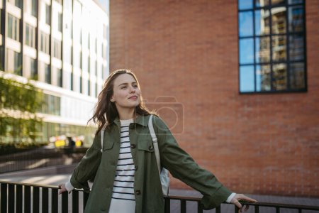 Foto de Retrato de una joven en una ciudad, de pie frente a un edificio de ladrillo rojo. - Imagen libre de derechos