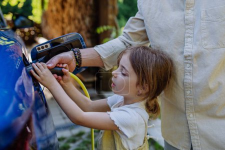 Photo for Father and his little daughter charging their electric car. - Royalty Free Image