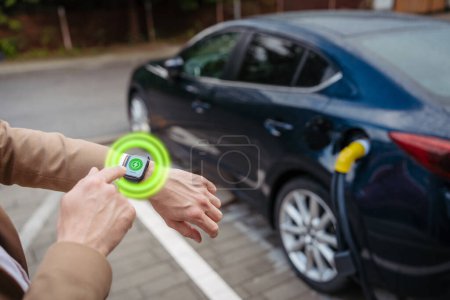 Photo for Close up of businessman with smartwatch, checking charging of the electric car. Picture with graphic element around smartwatch. - Royalty Free Image