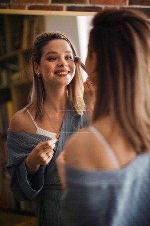 Téléchargez les photos : Jeune femme se maquillant, se regardant dans un miroir. - en image libre de droit