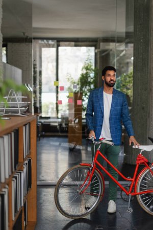Foto de Joven hombre multirracial con bicicleta en una oficina. - Imagen libre de derechos