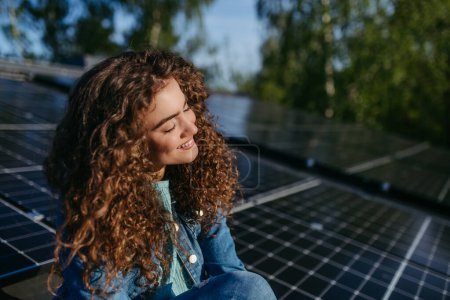 Téléchargez les photos : Portrait de jeune femme, propriétaire sur le toit avec panneaux solaires. - en image libre de droit