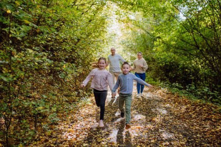 Foto de Familia feliz con niños corriendo en un bosque. - Imagen libre de derechos