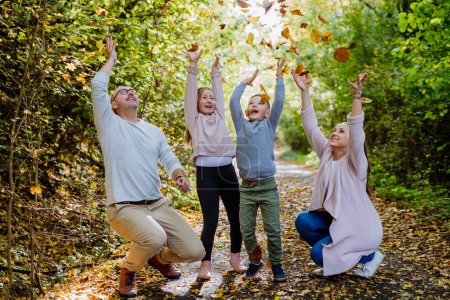Foto de Familia feliz divirtiéndose con el follaje en el bosque de otoño. - Imagen libre de derechos